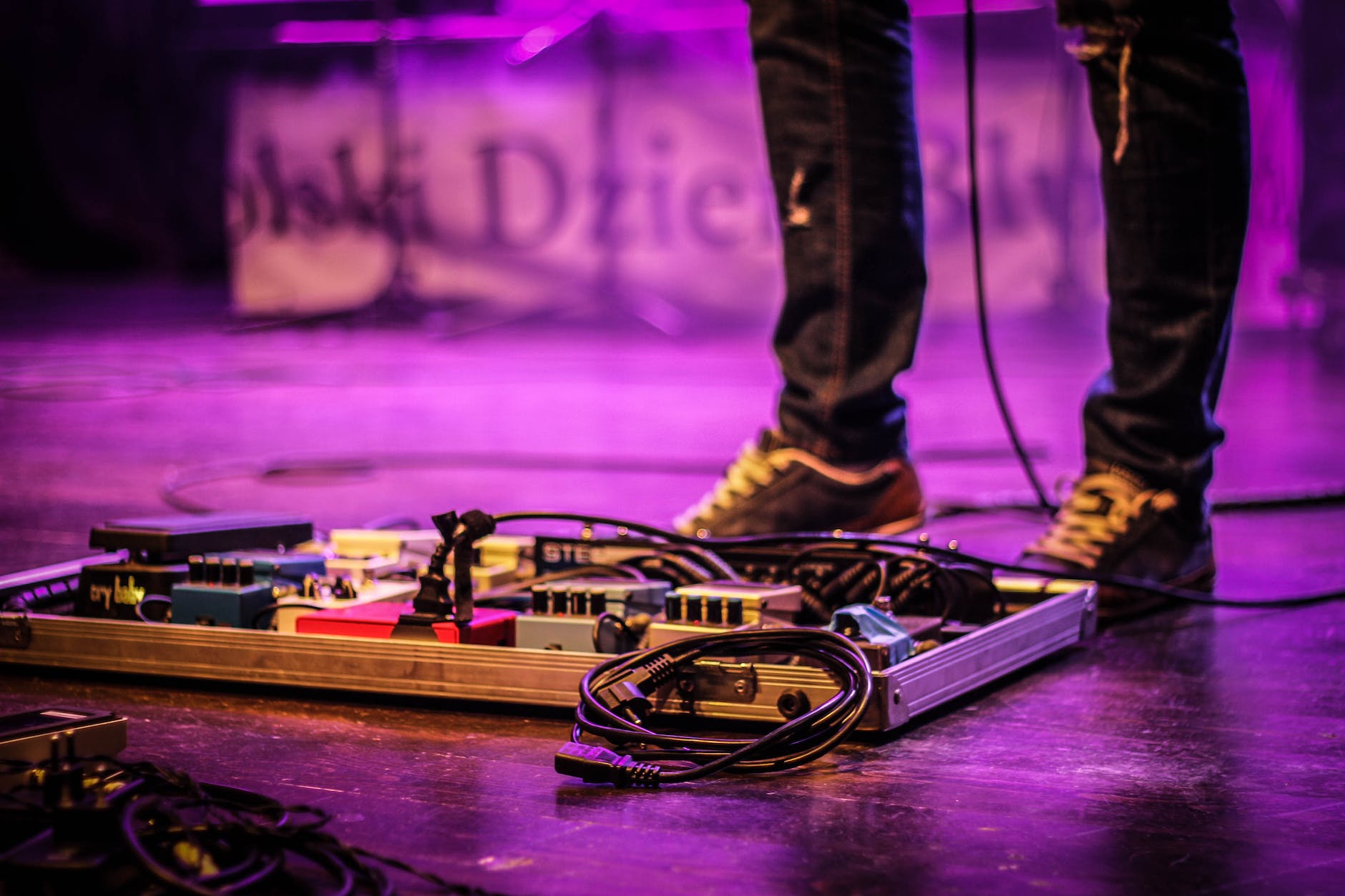 faceless musician with pedalboard in club